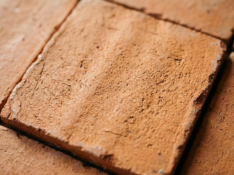 textured ceramic tile detail macro shot, matte terracotta finish